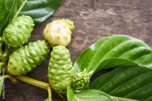 Fotografie noni fruit on wooden background - fresh ripe and raw noni leaf , Great morinda (