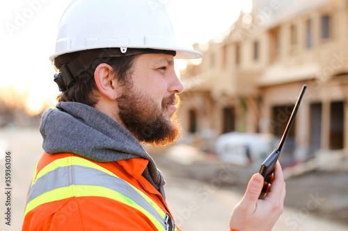 Portrait of european foreman talking by walkie talkie on construction site.