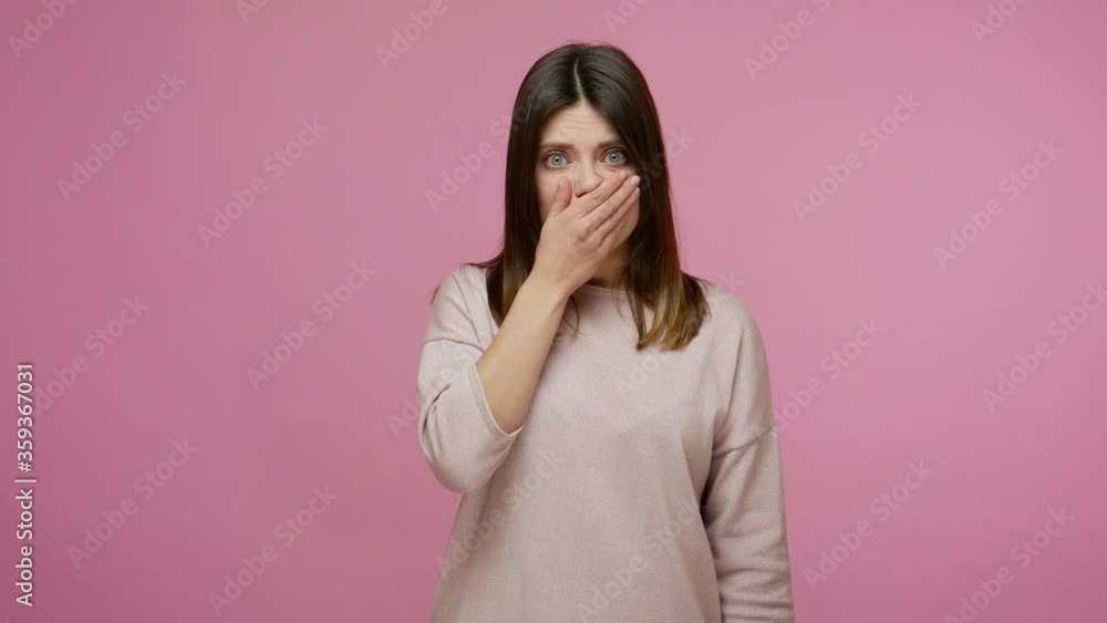 Terrified intimidated woman covering her mouth to keep silence, surprised by horrible truth holding breath and promising don't tell secret to anyone. indoor studio shot isolated on pink background Terrified intimidated woman covering her mouth to keep silence, surprised by horrible truth holding breath and promising don't tell secret to anyone. indoor studio shot isolated on pink background