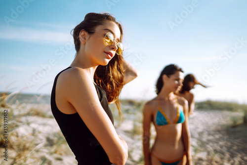 Group of happy young women walking on a beach. Four female friends strolling along the sea shore on a summer day, enjoying vacation.