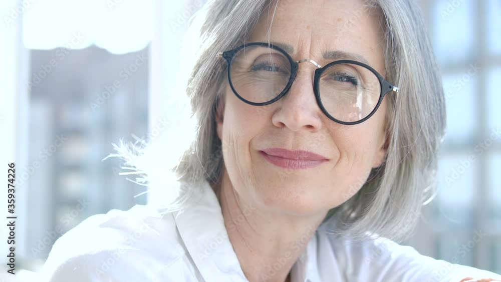Stylish senior woman in eyeglasses looking at cam, nice smile on wrinkled face Stylish senior woman in eyeglasses looking at cam, nice smile on wrinkled face