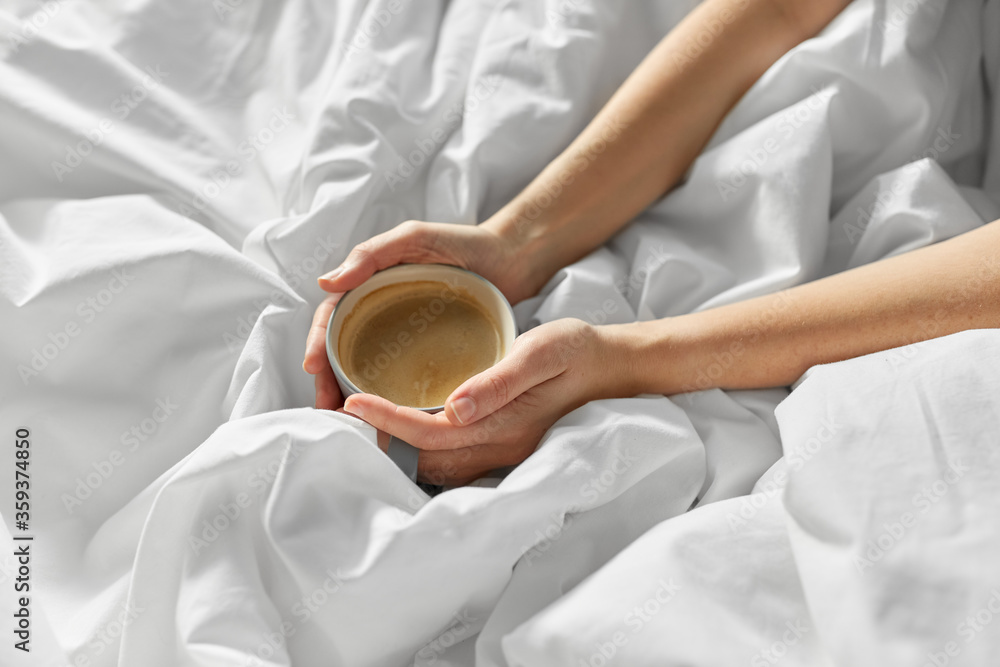 morning, drink and people concept - hands of young woman with cup of coffee in bed at home bedroom morning, drink and people concept - hands of young woman with cup of coffee in bed at home bedroom