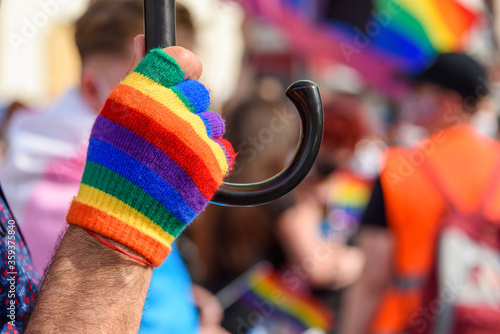 human hand in rainbow color glove. LGBT rainbow flag on foreground as a symbol of equality rights with blurred background. Equality rights for all people
