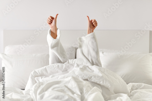 Fototapeta gesture, comfort and morning concept - hands of young woman in hotel robe lying