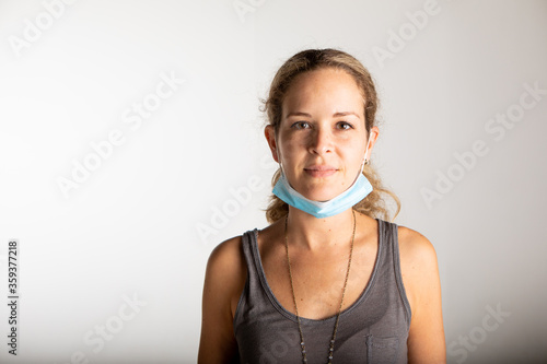 young woman wearing the surgical mask under the chin to get some air and show her face. 
