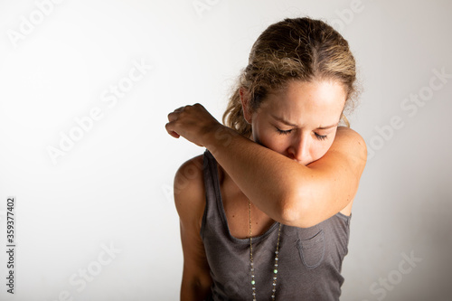 caucasian women couching into the arm in front of white wall.
