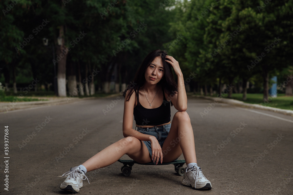 Young girl sitting on a skateboard in the city