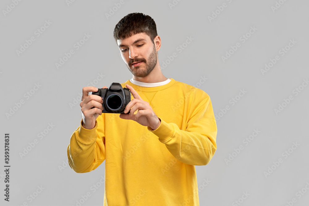 photography and people concept - young male photographer in yellow sweatshirt taking picture with digital camera over grey background photography and people concept - young male photographer in yellow sweatshirt taking picture with digital camera over grey background