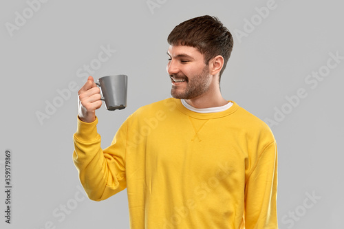 drinks and people concept - happy smiling young man with coffee cup over grey background