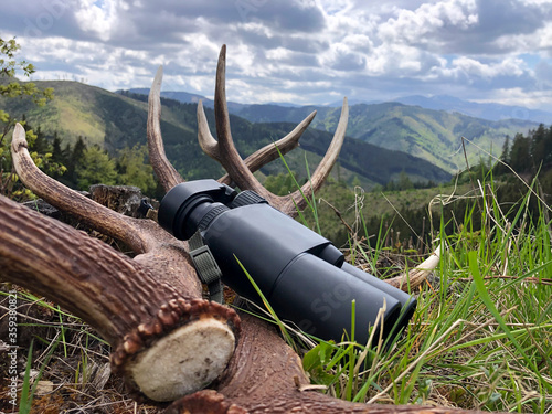 Deer antlers with mountains background. Binoculars aid in finding antlers