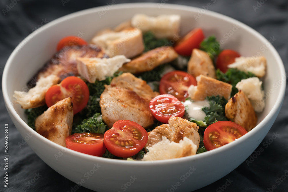 Caesar salad alternative with kale and turkey in white bowl Caesar salad alternative with kale and turkey in white bowl