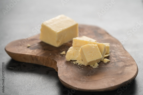 White cheddar cheese pieces on olive wood board