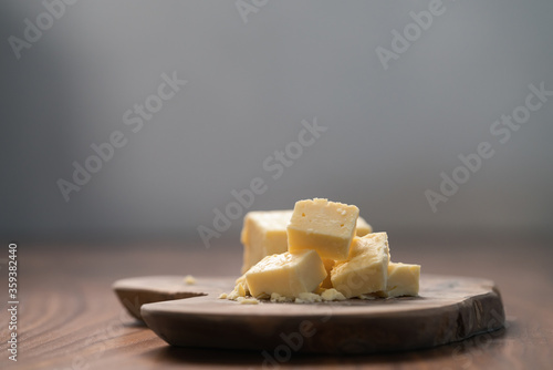 White cheddar cheese pieces on olive wood board