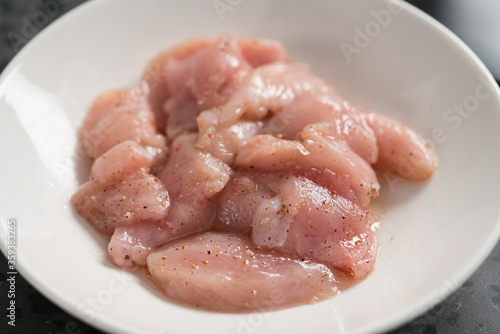 raw sliced chicken fillet meat in spices marinating in bowl