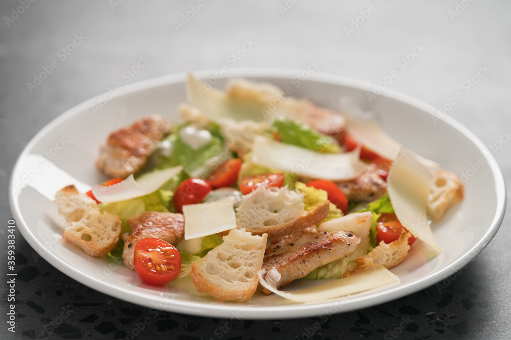 Fresh caesar salad with chicken and cherry tomatoes in white bowl