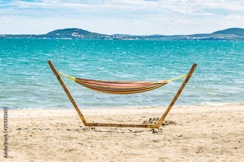 Tropical beach background as summer landscape with beach swing or hammock and white sand and calm sea for beach banner. Perfect beach scene vacation and summer holiday concept. Burgas beach, Bulgaria