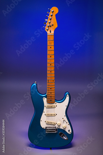 Blue electric guitar on the grey background with the blue spot. 