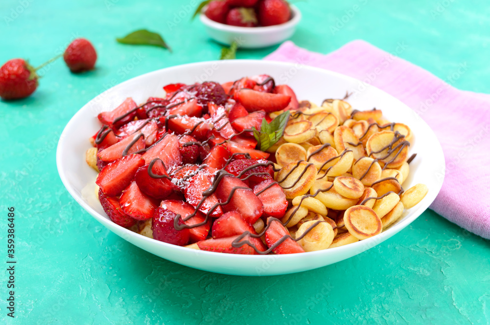 Pancake cereal in a bowl with fresh strawberries and nuts on a bright background. Tasty and trendy breakfast. Organic Dutch Mini-Pancakes. Foods trend. Pancake cereal in a bowl with fresh strawberries and nuts on a bright background. Tasty and trendy breakfast. Organic Dutch Mini-Pancakes. Foods trend.