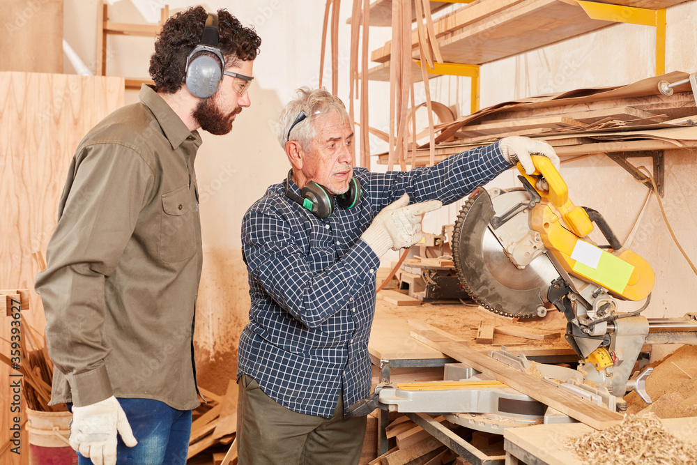Carpenter master and apprentice at the chop saw Carpenter master and apprentice at the chop saw