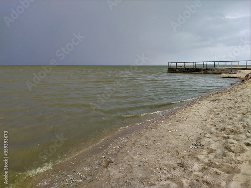 Sandy beach with muddy water before a thinderstorm