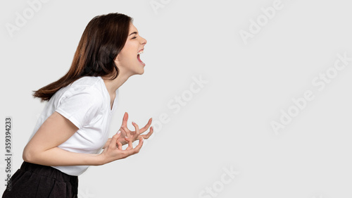Mad woman portrait. Horror frustration. Insane lady isolated screaming at light empty space.