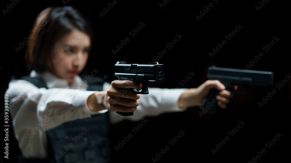 Woman wearing bulletproof vest shoots with gun at a target at indoor gun range. Woman wearing bulletproof vest shoots with gun at a target at indoor gun range.