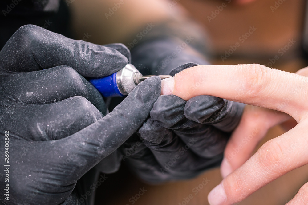 Hardware manicure in a beauty salon. Female manicurist is applying electric nail  file drill to manicure on female fingers. Mechanical manicure close-up.  Concept body care. Stock Photo | Adobe Stock