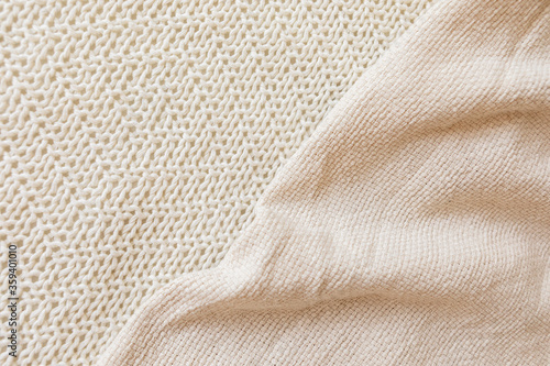Two soft beige knitted blankets lying diagonally with copy space. Retro abstract boho scandinavian rustic background with cloth for decorative design. Cosy warm seasonal interior concept