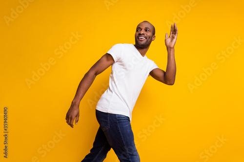 Profile side photo of charming cheerful candid afro american guy go spring walk wave hand say good bye wear trendy clothes isolated over shine color background photo