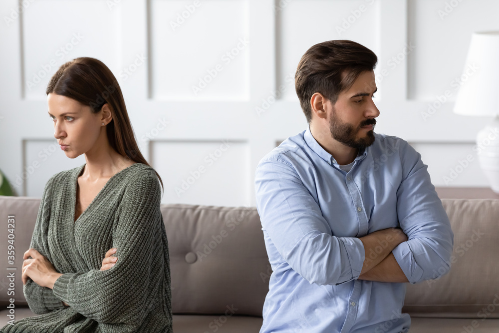 Angry stressed couple not talking after fighting, sitting back to back on couch separately, worried frustrated girlfriend and boyfriend not talking, family crisis or relationship problems
