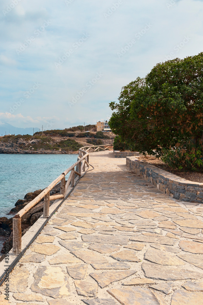 fragment of a stone path with wooden railings along the coast in the Greek resort town of Agios Nikolaos