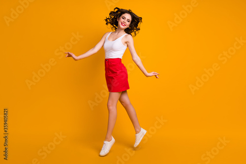 Full body photo of amazing lady jump high up good mood sunny day weekend hairdo flight wear white casual singlet red short mini skirt footwear isolated yellow color background