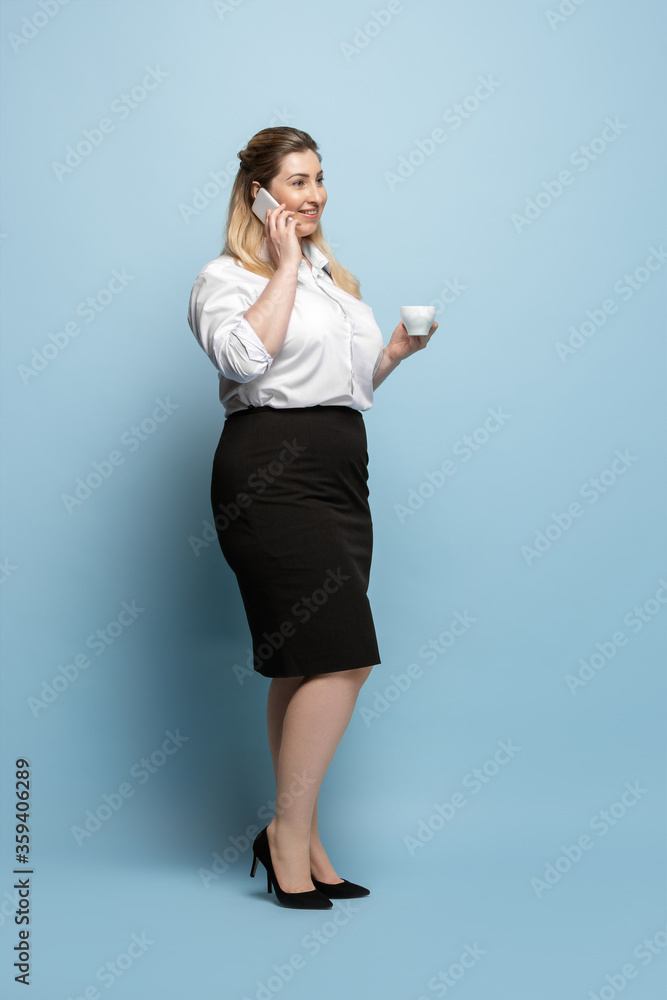 Talking. Young woman in office attire. Bodypositive female character, feminism, loving herself, beauty concept. Plus size businesswoman on blue background. Boss, beautiful. Inclusion, diversity. Talking. Young woman in office attire. Bodypositive female character, feminism, loving herself, beauty concept. Plus size businesswoman on blue background. Boss, beautiful. Inclusion, diversity.