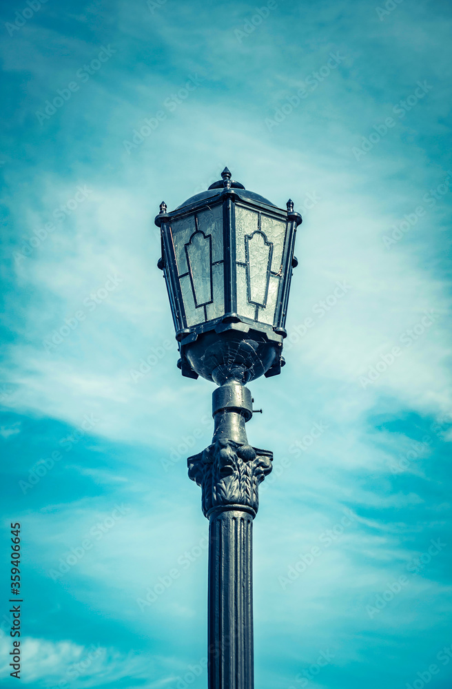 Old street lamp against the blue sky in clear weather
