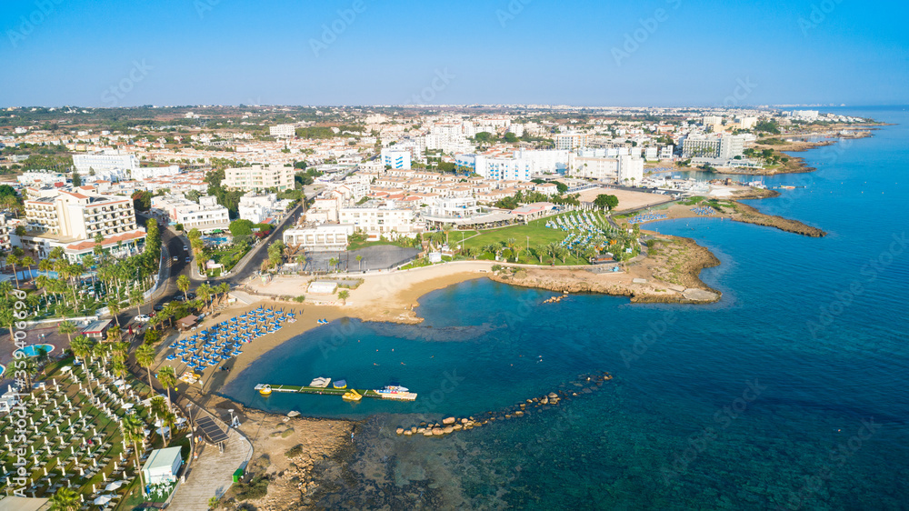 Aerial bird's eye view Pernera beach Protaras, Paralimni, Famagusta, Cyprus. The tourist attraction golden sand bay with sunbeds, water sports, hotels, restaurants, people swimming in sea from above.