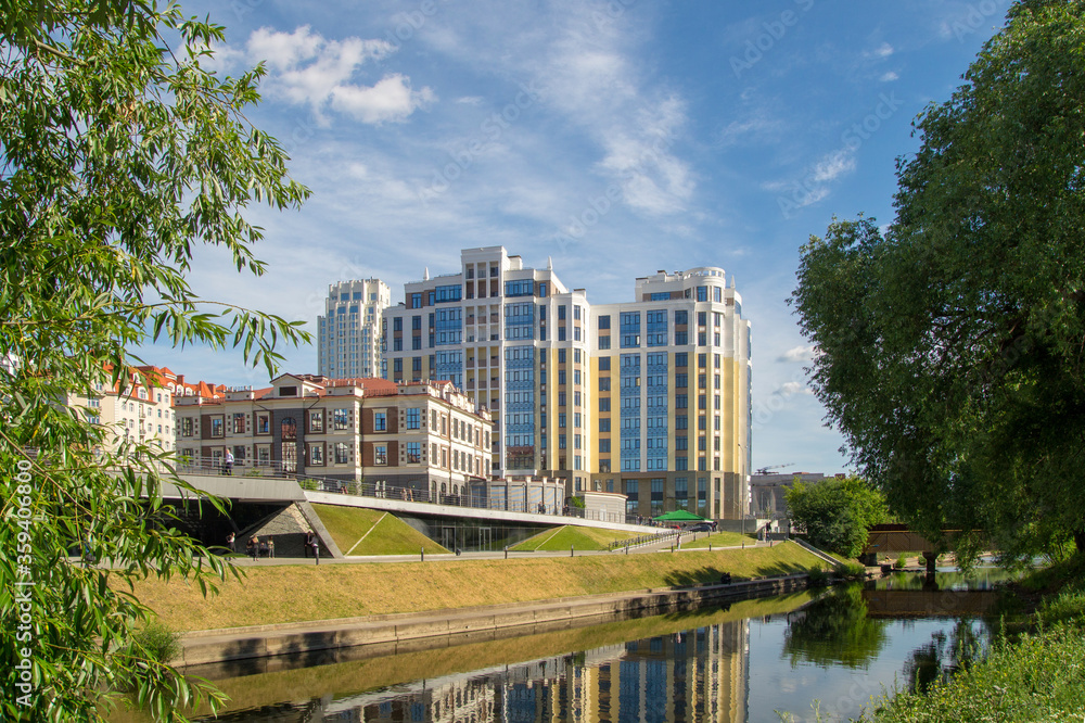 Buildings reflected in the water of a city park in sunny weather