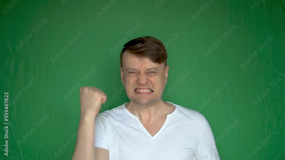 Careless adult man takes off the mask from his head and rejoices with beautiful eyes on a green background with daylight dark mask blue eyes Careless adult man takes off the mask from his head and rejoices with beautiful eyes on a green background with daylight dark mask blue eyes