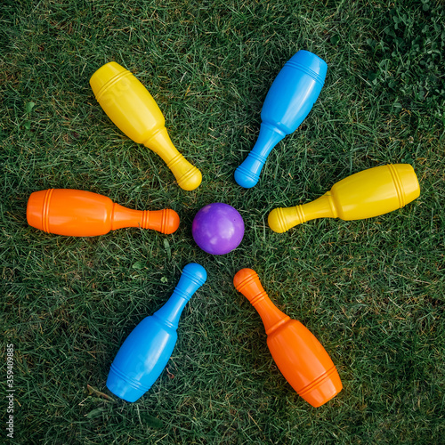 Children's set to play bowling on green grass. Ball and colored pins. Kid's game toy. Bowling colorful plastic pins. Active and interesting childhood concept.
