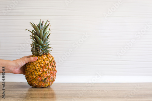 Female hand picking up a pineapple in the kitchen. Copy space