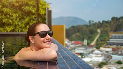 Pretty girl in black sunglasses spends time standing in swimming pool copyspace. travel concept