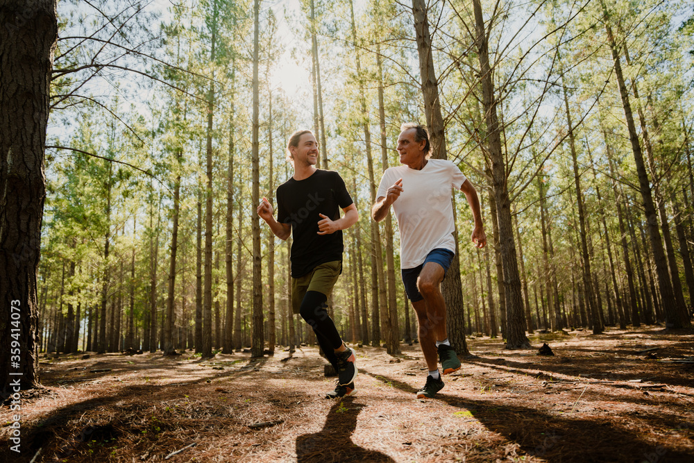 Fototapeta premium Father and son running in the woods together, exercising and keeping fit