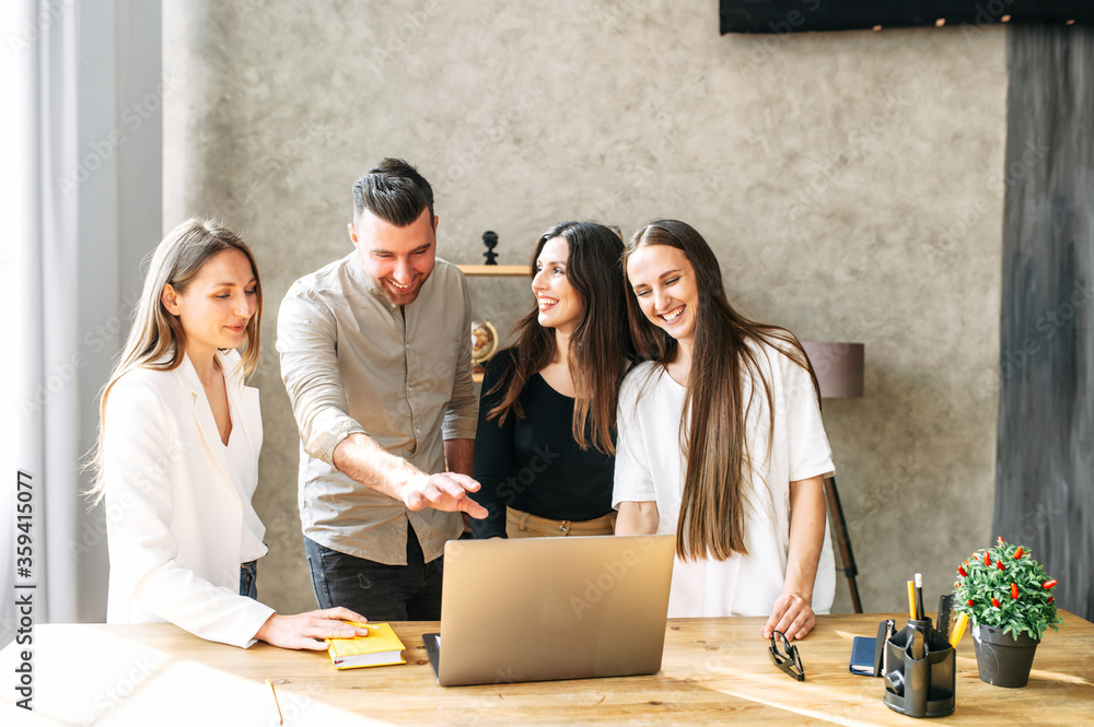 Employees discuss working moments in front of a laptop in a friendly atmosphere, smiling and laughing Employees discuss working moments in front of a laptop in a friendly atmosphere, smiling and laughing