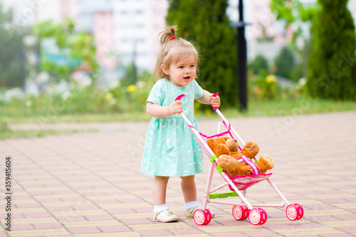 beautiful  cute baby child plays with baby stroller caring positive association care .walk rest in the park with mom