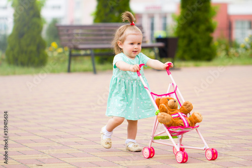 beautiful  cute baby child plays with baby stroller caring positive association care .walk rest in the park with mom