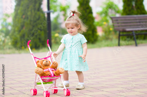 beautiful  cute baby child plays with baby stroller caring positive association care .walk rest in the park with mom