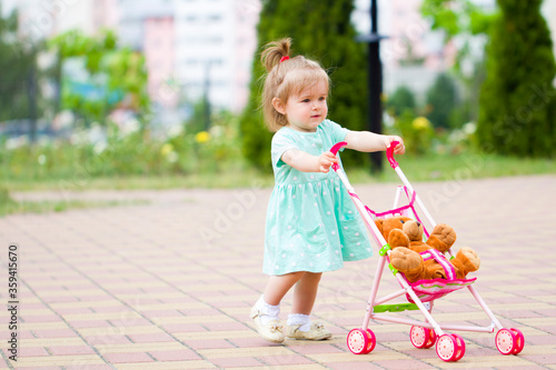 beautiful  cute baby child plays with baby stroller caring positive association care .walk rest in the park with mom