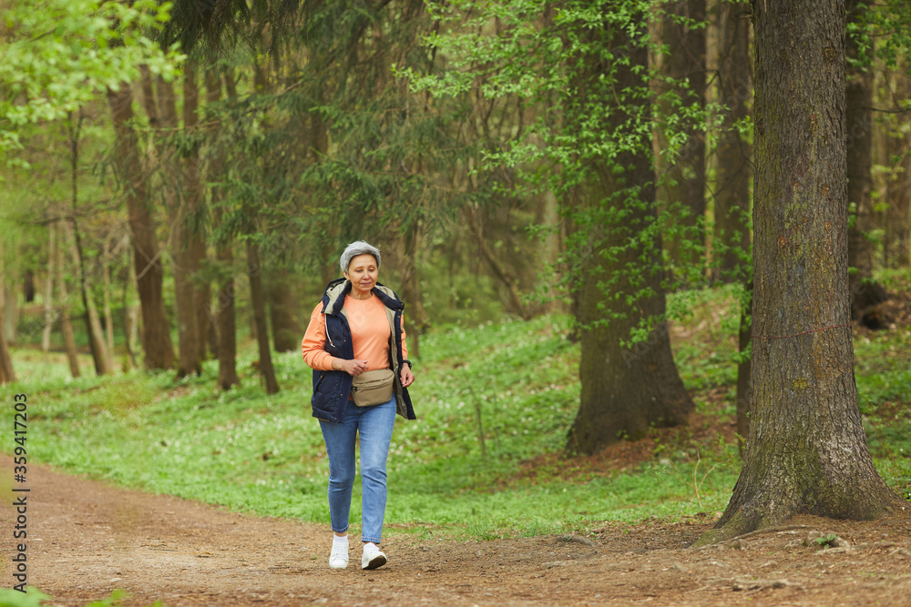 Wide angle portrait of active senior woman running during hike in beautiful autumn forest, copy space Wide angle portrait of active senior woman running during hike in beautiful autumn forest, copy space