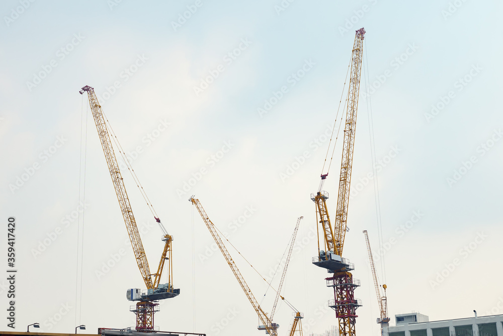 Construction cranes on a background of cloudy sky.