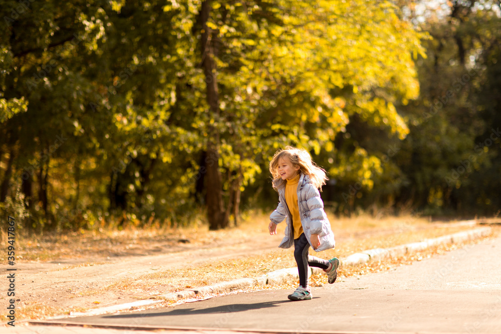 little girl in a coat in autumn runs in Park. active holidays with children in nature. little girl in a coat in autumn runs in Park. active holidays with children in nature.