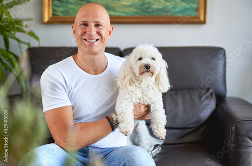 Handsome man with cute white dog at sofa
